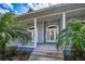Close-up of the beautiful front entrance featuring a charming porch and tropical landscaping at 5050 Limestone Dr, Port Richey, FL 34668