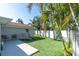 Large backyard featuring green turf, palm trees, lounge chairs, and a white fence for privacy at 5061 Ensign Loop, New Port Richey, FL 34652