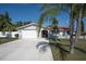 Charming home featuring a white exterior, well-manicured lawn, and a spacious driveway, complemented by tropical palm trees at 5061 Ensign Loop, New Port Richey, FL 34652