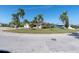 Scenic street view showcasing a well-maintained home with lush green lawns and swaying palm trees under a clear blue sky at 5061 Ensign Loop, New Port Richey, FL 34652