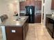 Kitchen island with a granite countertop, stainless steel sink, and modern black appliances at 5143 Sable Chime Dr, Wimauma, FL 33598