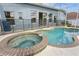 An in-ground pool and spa sit below a screened enclosure with backyard views at 5357 Greystone Dr, Spring Hill, FL 34609