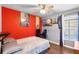 Cozy bedroom featuring hardwood floors, a bright red accent wall, and a window with a view of the backyard pool at 5903 War Admiral Dr, Wesley Chapel, FL 33544