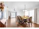 Well-lit dining room with hardwood floors, a modern chandelier, large windows, and a view of the front yard at 5903 War Admiral Dr, Wesley Chapel, FL 33544