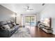 Comfortable living room with hardwood floors, a large leather sofa, a ceiling fan, and access to the backyard pool at 5903 War Admiral Dr, Wesley Chapel, FL 33544