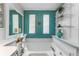 Large soaking tub with teal accent wall, white vanities, and decorative shelving in this bright bathroom at 610 Cobia Way, Oldsmar, FL 34677