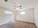 A cozy bedroom with a ceiling fan, neutral walls, and natural light from multiple windows at 6301 Baldwyn Ave, New Port Richey, FL 34653