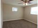 Cozy bedroom with plush carpeting, a ceiling fan, and natural light from two windows at 6301 Baldwyn Ave, New Port Richey, FL 34653