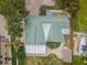 Aerial view of a home with a green roof, fenced yard, boat parking, and surrounding greenery at 646 Riverside Dr, Tarpon Springs, FL 34689