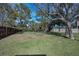 Spacious backyard featuring lush green grass, mature trees, and a combination of wooden and white fencing at 646 Riverside Dr, Tarpon Springs, FL 34689
