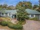 Charming single-story home featuring a well-manicured lawn, mature trees, and a brick-paved driveway at 646 Riverside Dr, Tarpon Springs, FL 34689