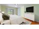 Bright bedroom with wood floors, ceiling fan, slider, and large dresser with mounted TV at 6741 Northlake Dr, Zephyrhills, FL 33542