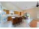 Eat-in kitchen features an island with seating, tile flooring, oak cabinets and a sliding door to outdoor space at 6741 Northlake Dr, Zephyrhills, FL 33542