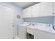 Functional laundry room with washer, dryer, utility sink, and storage cabinets at 6741 Northlake Dr, Zephyrhills, FL 33542