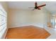 Bright living room with hardwood floors, ceiling fan, neutral paint, and a large grid window overlooking outdoor landscape at 6741 Northlake Dr, Zephyrhills, FL 33542