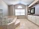 Bright bathroom featuring a soaking tub, marble tile, double vanity, and a arched window offering natural light at 7104 Hummingbird Ln, New Port Richey, FL 34655