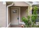 Inviting entryway features a light-colored front door with decorative glass, complemented by a small bush, and a charming exterior light at 7292 Sherman Hills Blvd, Brooksville, FL 34602