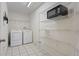Bright laundry room with white appliances, wire shelving and tile flooring provides practicality and organization at 7292 Sherman Hills Blvd, Brooksville, FL 34602