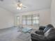 Bright living room with a ceiling fan, plush carpeting, and large windows offering natural light at 7292 Sherman Hills Blvd, Brooksville, FL 34602
