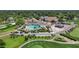 Aerial view of a clubhouse with a pool, cabana, and golf cart parking near a sprawling green golf course at 8157 Hidden Hills Dr, Spring Hill, FL 34606