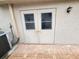 Exterior view of a house featuring double doors, a brick patio and an air conditioning unit at 8157 Hidden Hills Dr, Spring Hill, FL 34606