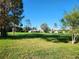 Beautiful green space featuring a large expanse of grass with mature trees and neighborhood homes in the distance at 8157 Hidden Hills Dr, Spring Hill, FL 34606