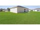 Exterior rear view of the property featuring a spacious backyard and a sliding door entrance at 8983 Wade St, Brooksville, FL 34613