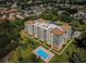 Aerial view of a tan condo complex surrounded by lush greenery and community pool at 9000 Commodore Dr # 302, Seminole, FL 33776