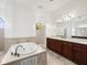 Bathroom featuring dark wood cabinetry, a soaking tub, and neutral tile work at 10188 Whisper Ridge Trail Trl, Weeki Wachee, FL 34613