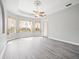 Spacious bedroom with tray ceiling, ceiling fan, hardwood flooring, and large windows at 10188 Whisper Ridge Trail Trl, Weeki Wachee, FL 34613