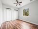This bedroom has hardwood floors, ceiling fan, and large window overlooking trees at 10188 Whisper Ridge Trail Trl, Weeki Wachee, FL 34613