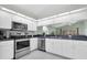 Bright kitchen featuring stainless steel appliances, white cabinetry and views to the backyard at 11700 Leda Ln, New Port Richey, FL 34654