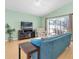 Bright living room featuring a plush blue sofa, light hardwood floors, and sliding glass doors to the screened lanai at 11700 Leda Ln, New Port Richey, FL 34654