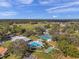 Aerial view of a refreshing community pool with lounge chairs, palm trees, and nearby tennis courts at 13032 Pinnacle Ln, Hudson, FL 34669