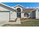 Inviting front entrance with a stylish blue door, arched window, and neatly landscaped mulch beds at 3606 Dow Ln, Spring Hill, FL 34609