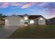 Charming single Gathering home features a 2-car garage and well-maintained lawn under a beautiful sunset sky at 3606 Dow Ln, Spring Hill, FL 34609