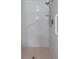 White tiled shower featuring a shower head, grab bar, shelf, and a textured pink tiled floor at 3606 Dow Ln, Spring Hill, FL 34609