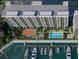 An aerial view of the condo building with a pool, tennis court, boat dock, and waterfront access at 5015 Us Highway 19 # 405, New Port Richey, FL 34652