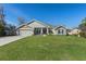 Charming home features a lush green lawn, two-car garage, and covered porch with stone accents at 5139 Jenson Ave, Spring Hill, FL 34608
