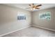 Bedroom with light gray walls, tile floor, ceiling fan, and two windows providing natural light at 5345 Carlton Rd, New Port Richey, FL 34652