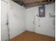 Unfinished basement space shows a white block wall and a door, with electric service lines hanging loosely above at 6414 Kelso Dr, Port Richey, FL 34668