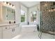 Elegant bathroom featuring soaking tub, glass shower with custom tile, and natural light at 6470 Summit View Dr, Brooksville, FL 34601
