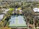 Aerial view of the community tennis courts with lush surroundings and beautiful landscaping at 8404 Winding Wood Dr, Port Richey, FL 34668