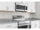 Modern kitchen featuring stainless steel oven and microwave with white cabinets and granite countertops at 9062 Wade St, Brooksville, FL 34613