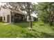 Scenic view of the backyard showing lawn, mature trees, and the back of the house at 9405 Palm Haven Ct, New Port Richey, FL 34655