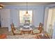 Bright dining room with round glass table, wood chairs, modern light fixture, and tile flooring at 10936 Keys Gate Dr, Riverview, FL 33579