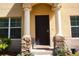 Inviting front entrance featuring a dark wood door, stone pillar bases, and a charming, covered entryway at 10936 Keys Gate Dr, Riverview, FL 33579