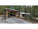 Exterior view of a rustic carport and storage building with metal roof in a natural wooded setting at 11617 Duda Rd, Hudson, FL 34667