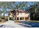 Exterior elevation of stilted home featuring a large shade tree, a carport, and stairs to the front door at 12724 Circle Lake Dr, Hudson, FL 34669
