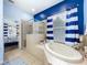 Bright bathroom featuring a soaking tub with striped curtains and a glass enclosed shower at 13304 Mandalay Pl, Spring Hill, FL 34609